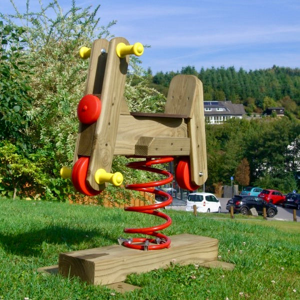 Federwipper Motorrad aus Holz auf der Wiese mit Blick auf die Landschaft