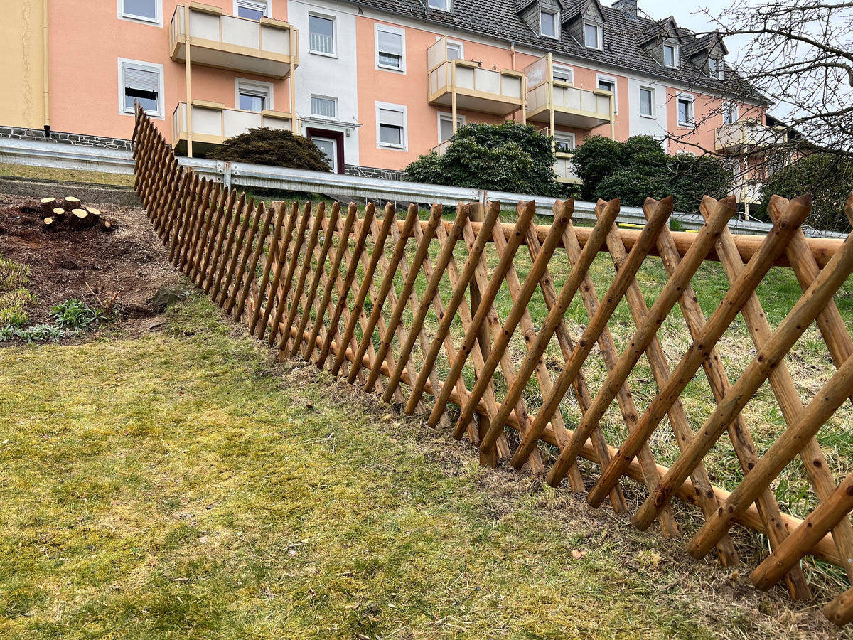Langer Jägerzaun aus Holz als Einfassung einer Rasenfläche vor einem Wohnhaus