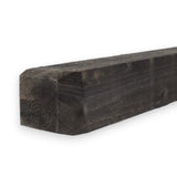 Stumpfes Ende eines schwarzen Vierkantpfostens aus Holz im Detail