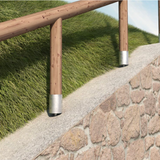 Runde Pfostenträger mit Rundholzpfosten eines Holzgeländers auf einer Natursteinmauer