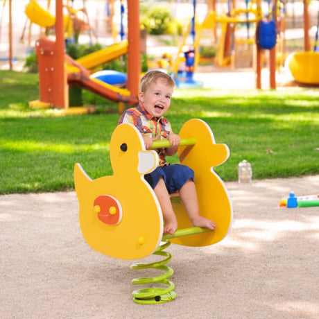 Kind wippt auf dem gelben Federwipper Ente auf einem öffentlichen Spielplatz