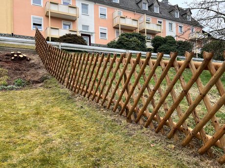 Langer Jägerzaun aus Holz als Einfassung einer Rasenfläche vor einem Wohnhaus