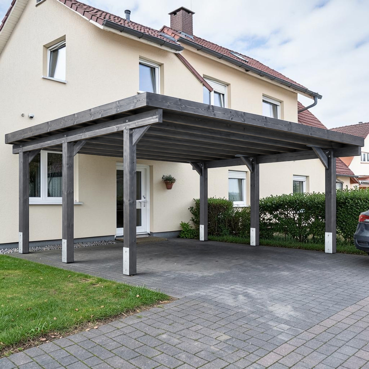 Grau lasierter Holz Doppelcarport über gepflasterter Einfahrt vor einem Wohnhaus
